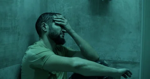 Pensive man sitting under shower in illuminated bathroom Stock Footage 271159344