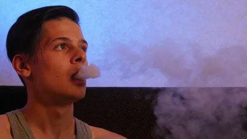 Pensive man smoking e-cigarette at home Видео 106028667