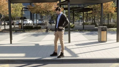 Pensive Man Standing Alone at Bus Stop in Urban Area Stock Footage 293680292