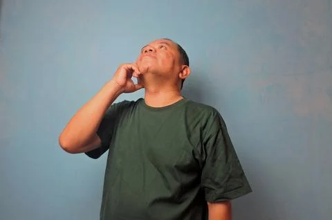 Pensive Man Thinking and Looking Up Against Blue Wall Stock Photos
