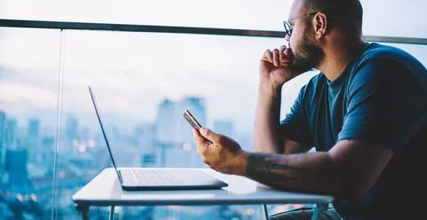 Pensive man touching chin using smartphone Stock Photos