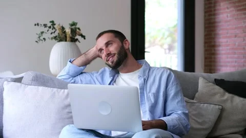 Pensive man using laptop daydreaming on couch Stock Footage 335588525