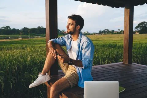 Pensive man using smartphone and laptop for remote work on nature Stock Photos