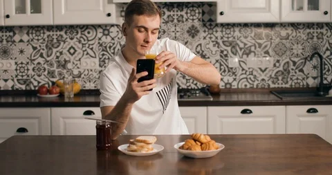 Pensive Man Using Smartphone in Kitchen Видео 103825290