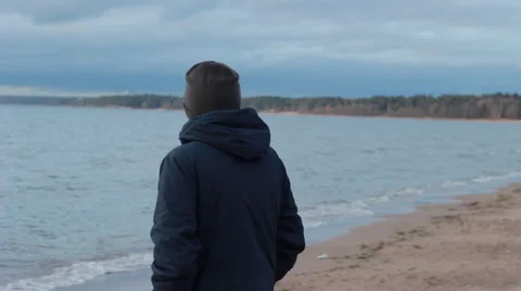 Pensive man walks alone on the beach in winter Video stock 61402500