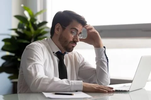 Pensive manager looking at computer screen, making difficult decision. Stock Photos