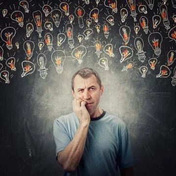 Pensive middle age man, keeps hand under chin, biting his finger nails, nervo Stock Photos