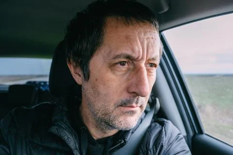 Pensive middle aged man inside a car, focused expression while driving, rea.. Stock Photos