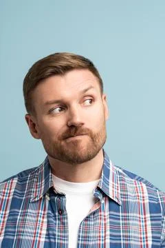Pensive middle aged man pursing lips look in the upper right corner, makes Stock Photos