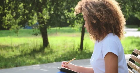 Pensive mixed race female handwriting paper notes in notepad page use pencil at Stock Footage 189279853