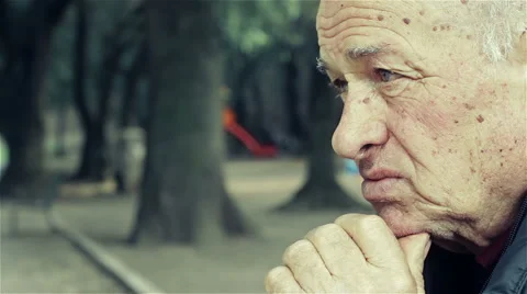 Pensive old man sitting alone with a park in background Video stock 48058146