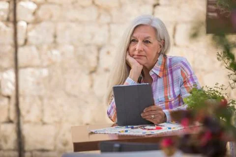 Pensive older Caucasian woman using digital tablet Stock Photos