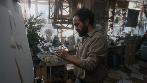 Pensive Painter Smoking Cigarette while Painting on Canvas in His Studio Stock Footage 334684349