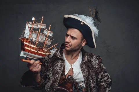 Pensive pirate looking at tiny toy ship 库存照片