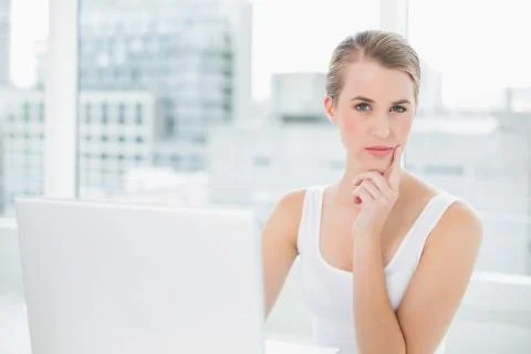 Pensive pretty blonde using her laptop Stock Photos