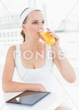 Pensive pretty sportswoman drinking orange juice Stock Photos