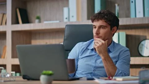 Pensive programmer looking computer in morning. Confident man watching online 写真素材
