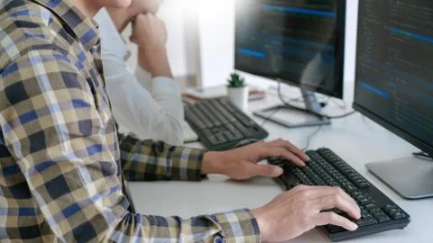 Pensive programmer working on desktop pc programming code technologies or web 库存照片