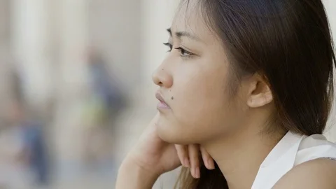 Pensive sad Asian woman sitting alone deep in her thoughts  Stock Footage