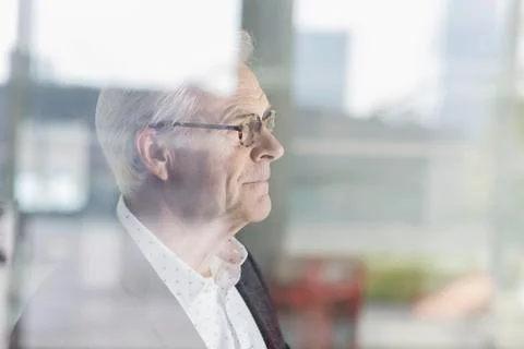 Pensive senior businessman looking out office window Stock Photos