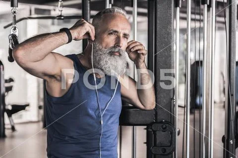 Pensive senior male is listening to music in athletic center Stock Photos