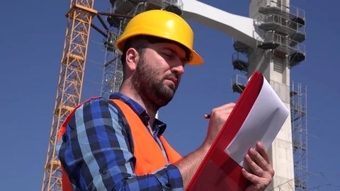 Pensive thoughtful architect rubbing his chin supervisor writing on clipboard 4K Stock Footage 76310768