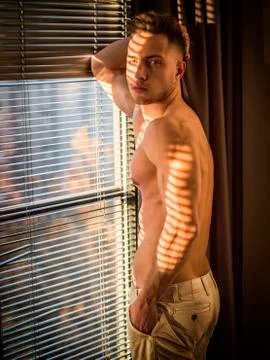 Pensive topless man in shadow stripes from window Stock Photos