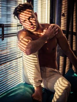 Pensive topless man in shadow stripes from window Stock Photos
