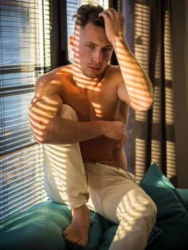 Pensive topless man in shadow stripes from window Stock Photos