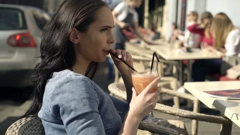 Pensive woman drinking juice sitting in cafe in city Stock Footage