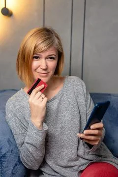 Pensive woman thinking while using her smartphone on the sofa Stock Photos