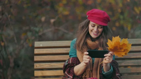 Pensive woman using phone while sitting on bench in city park Stock-Footage 252757685