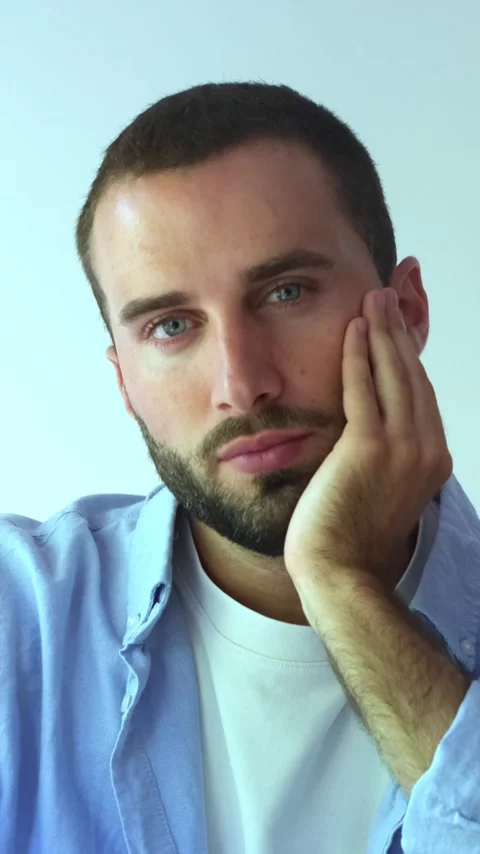 Pensive young bearded man with blue eyes looking at the camera and then away Stock Footage 345114682