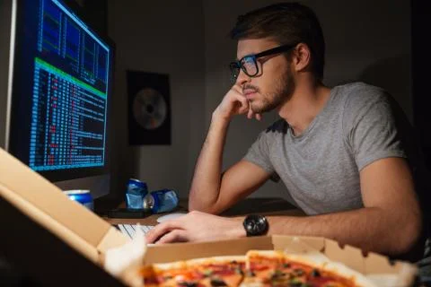 Pensive young developer in glasses coding at home Foto stock