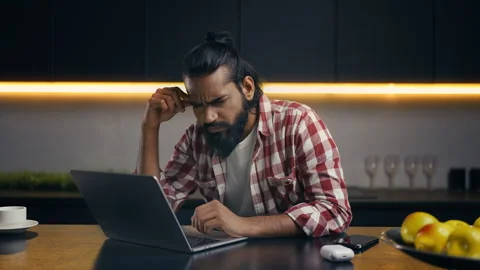 Pensive young Indian developer working late on laptop, focused on project Stock Footage 313281879