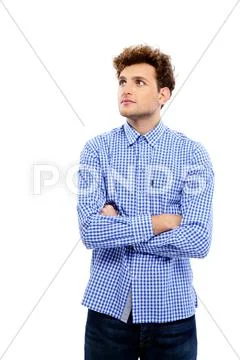 Pensive young man with arms folded standing over white background Stock Photos