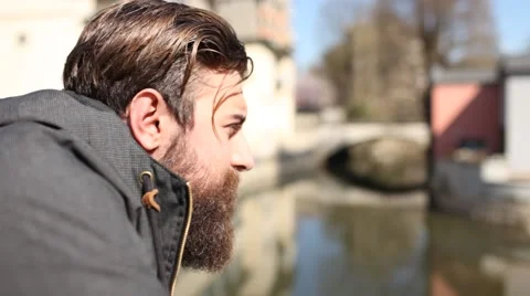 Pensive young man with a beard watching the river Stockbeeldmateriaal 61605915