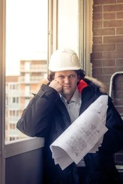 Pensive young man builder in hard hat standng and thinking. Soft focus, toned. Stock Photos