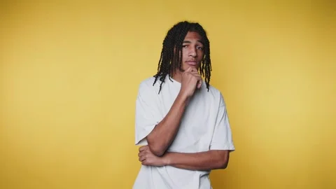 Pensive young man with dreadlocks poses on yellow background, showcasing th.. Stock Footage 313280322