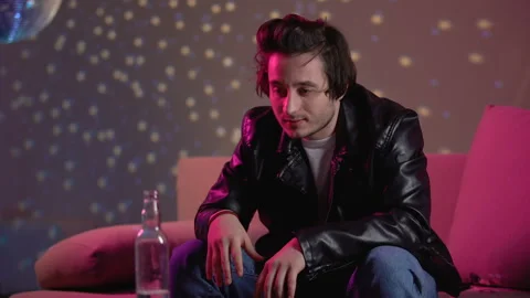Pensive young man drinking alcohol from bottle at party, addiction problem Stock Footage 105135879