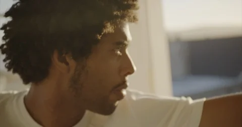 Pensive young man looking out his window at the sea. Vidéo 88373626
