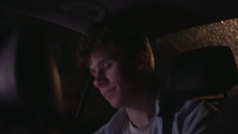 Pensive young man sitting in the back of a car looks out the window on a rainy Stock Footage 344295203
