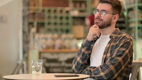 Pensive Young Man Sitting in Cafe and Thinking Stock Footage 134884428