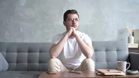 Pensive Young man Sitting on Sofa and Thinking at Home. 库存影片 137955214