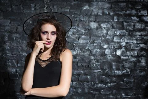 Pensive young witch plotting something in studio. Stock Photos