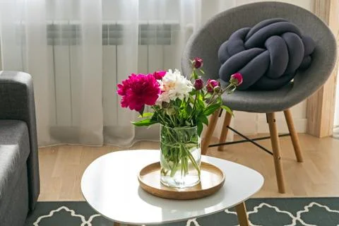 Peonies in the vase standing on the small table in the living room Stock Photos