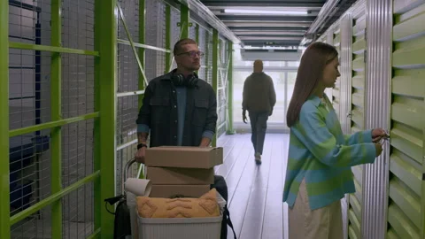 People Accessing Storage Unit with Cart Full of Boxes in Green Facility Stock Footage 290519973