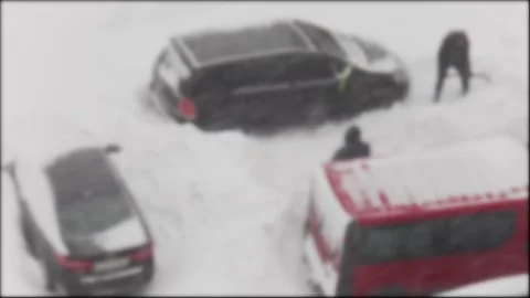 People actively clear deep snow from around cars stuck on a heavily snow-covered Stock Footage 329214231