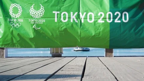 People and a dog walking in front of Tokyo 2020 olympic games flaglet in odaiba Stock Footage 124740455