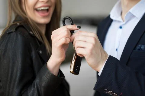 People and ownership concept - close up of car salesman giving key to new owner Stock Photos